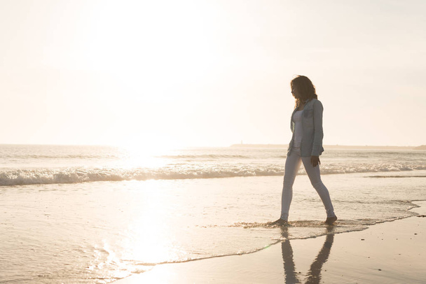 Kaunis nainen nauttii auringonlaskusta rannalla
 - Valokuva, kuva