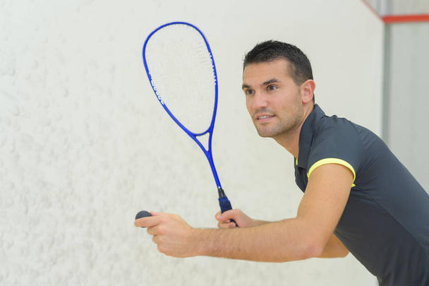 Man poised to serve playing squash - Foto, afbeelding