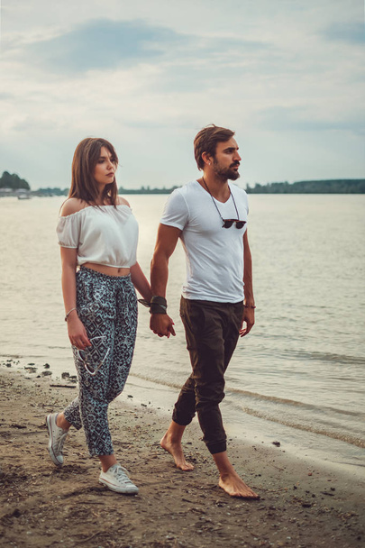 Serious and sad couple holding hands while walking on the beach - Valokuva, kuva