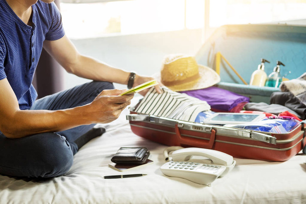 Young man hurring up to meeting and talking by phone and taking notes packing for Preparation travel suitcase at home. - Foto, imagen