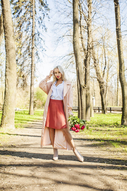 Smiling woman fashion model with flowers outdoors. Blonde female model - Foto, afbeelding