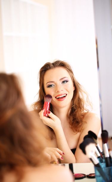 Young beautiful woman making make-up near mirror - Фото, изображение