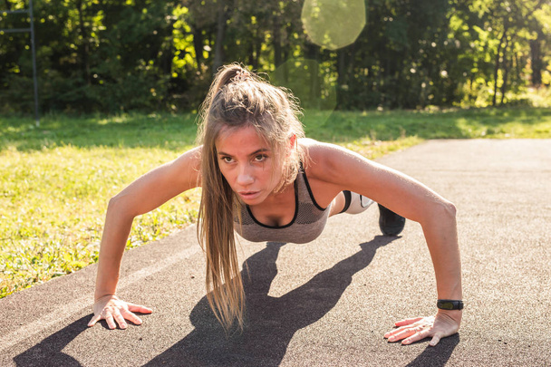 Young fit woman exercising by doing push-ups outdoors - Foto, immagini