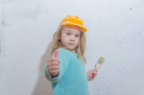 child worker, Builder, girl in a helmet paints the wall - Photo, image