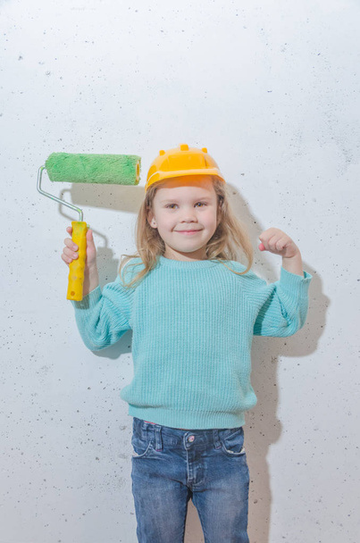 child worker, Builder, girl in a helmet paints the wall - Photo, Image