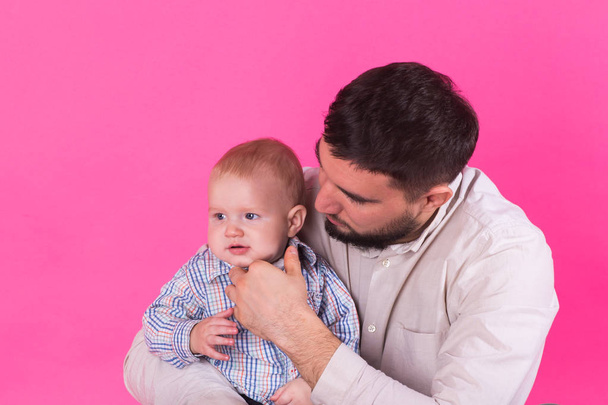 Baby in the daddy hands. Pink background. - Photo, Image