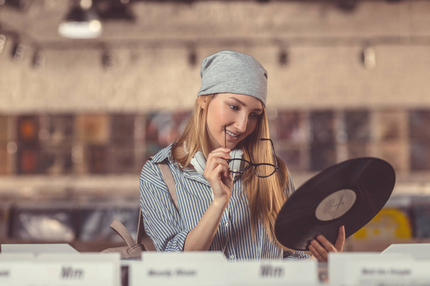 Rapariga sorridente com um disco de vinil na loja
 - Foto, Imagem