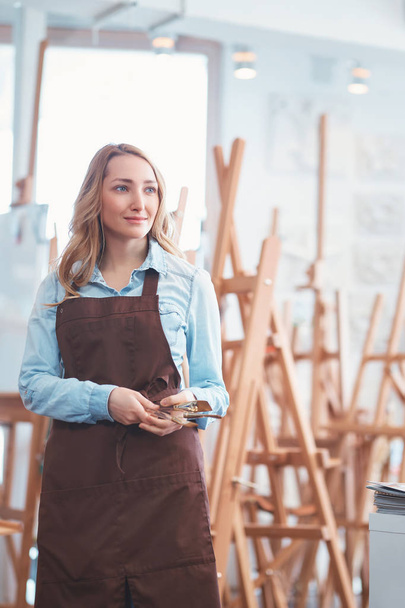 Young attractive girl in an apron in the art shop - Photo, Image