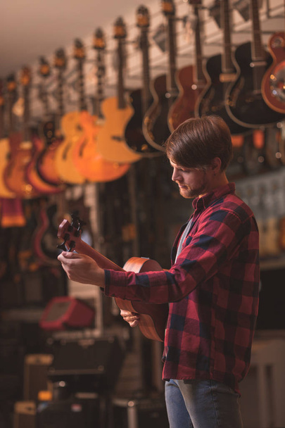 Giovane che suona su un ukulele in un negozio di musica
 - Foto, immagini