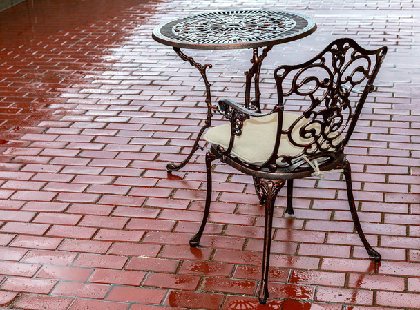 透かし彫りの金属テーブルと雨の後の屋外カフェで椅子 - 写真・画像