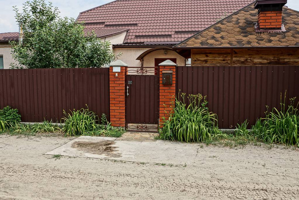 hnědý kovový plot a dveře na ulici v trávě u silnice - Fotografie, Obrázek