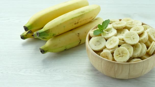 テーブルの上から木製のボウルの中のバナナと全体のバナナをスライス  - 映像、動画