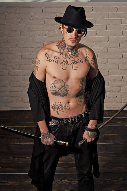 Honor and dignity. Warrior in black hat and open clothes showing tattooed torso - Valokuva, kuva