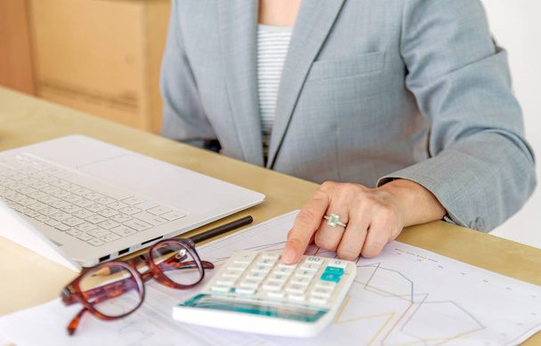 Business woman working with laptop, calculator, eyeglasses and report data on wood desk in office. - Фото, зображення