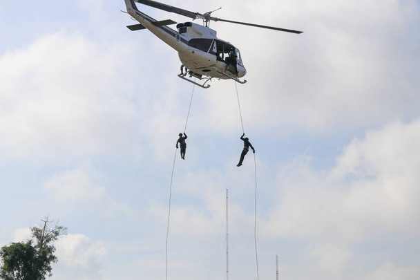 Soldaat abseilen van de helikopter in blauwe hemel met vervaging propeller - Foto, afbeelding