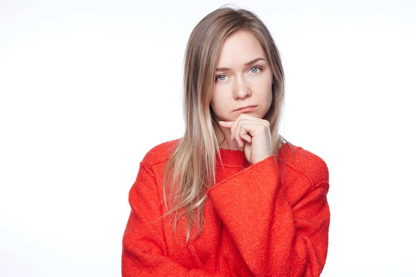 Headshot of unhappy frustrated young Caucasian female having puzzled expression, holding hand on his cheek and keeping arms folded. Sad American woman dressed in red sweater feeling bored or depressed - Foto, Imagem
