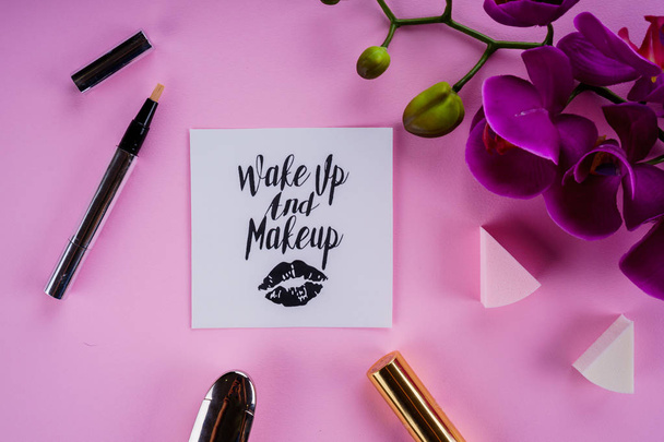 herramientas de maquillaje sobre un fondo rosa y flor de orquídea
 - Foto, Imagen