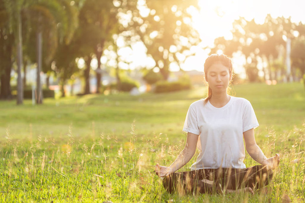 Pretty asian woman doing yoga exercises in the park. Used for relax and healthy concept - Photo, Image