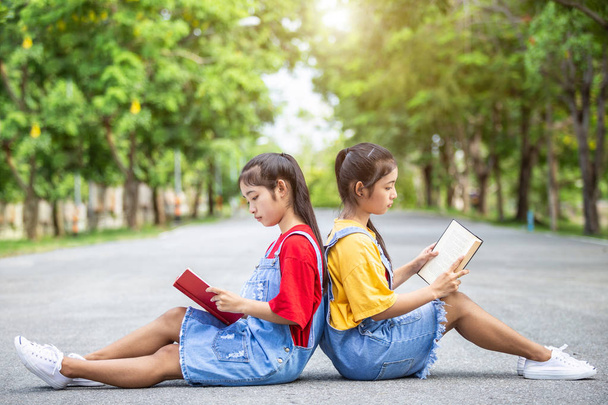 hübsche asiatische Zwillingsmädchen oder Studenten, die im öffentlichen Park ein Buch lesen. Bildungskonzept genutzt - Foto, Bild