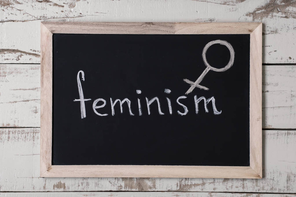The word "feminism" and venus symbol at blackboard, top view - Zdjęcie, obraz
