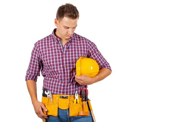 Attractive young repairman with yellow helmet and tool belt on isolated background - Фото, зображення