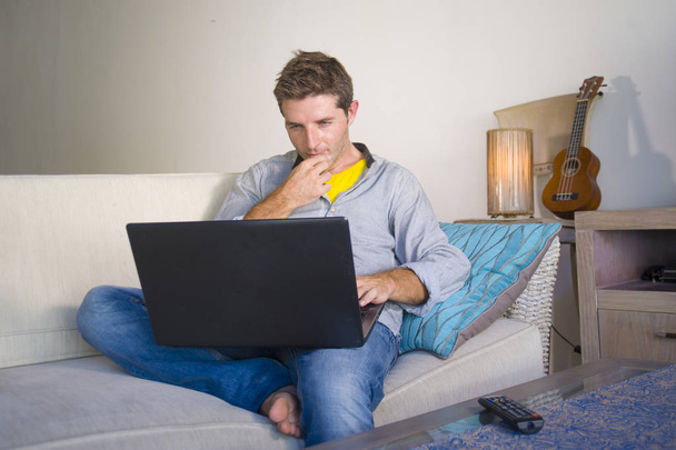 young attractive and successful man working from home living room sitting on couch networking on laptop computer happy in freelancer job and independent business lifestyle concept - Fotó, kép