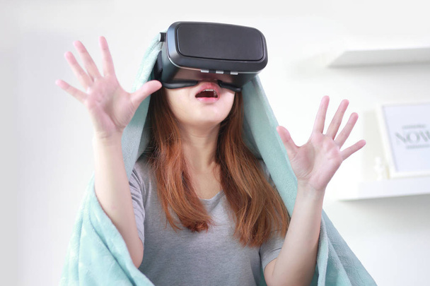 Mujer joven con gafas de realidad virtual en casa. Un auricular de realidad virtual es un dispositivo montado en la cabeza que proporciona realidad virtual para el usuario
. - Foto, imagen