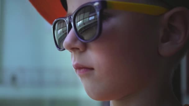 Portret dziecka w okulary, które właśnie się uśmiechać, chłopiec ogranicza jego emocje - Materiał filmowy, wideo