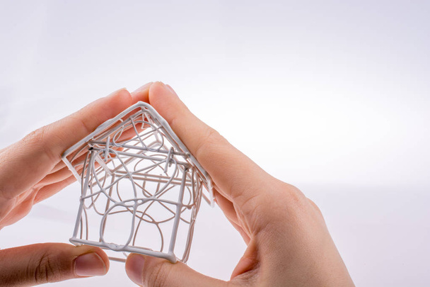 Little  model house made of white metal wire in hand - Fotoğraf, Görsel