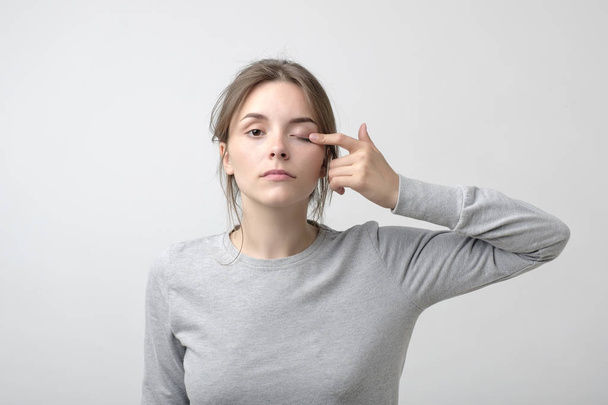 Женщина дотрагивается до глаза, чтобы показать, что у неё проблемы со зрением. Проблемы со здоровьем Концепция миопии или астигматизма
 - Фото, изображение