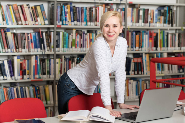 Portrait d'un étudiant attrayant faisant du travail scolaire avec un ordinateur portable à la bibliothèque
 - Photo, image
