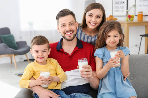 Happy family with glasses of milk in living room - Fotoğraf, Görsel
