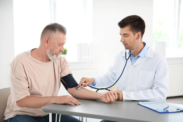 Doctor measuring patient's blood pressure in hospital - Foto, imagen