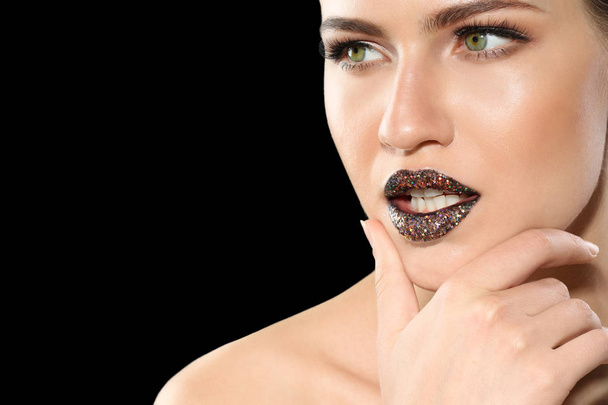 Beautiful young model with creative lips makeup on black background - Photo, Image