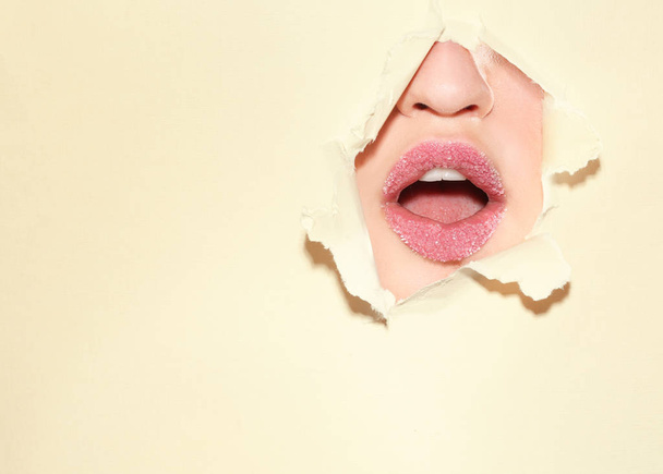 View of beautiful young woman with sugar lips through hole in color paper - Foto, imagen