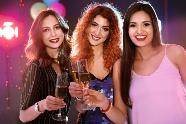Young women chinking glasses in nightclub. Birthday party - Фото, изображение
