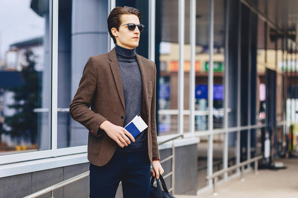 stylish attractive guy in jacket with passport and tickets travels - 写真・画像