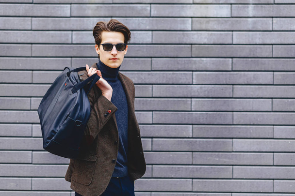 stylish guy in jacket and sunglasses against the background of wall - Foto, afbeelding