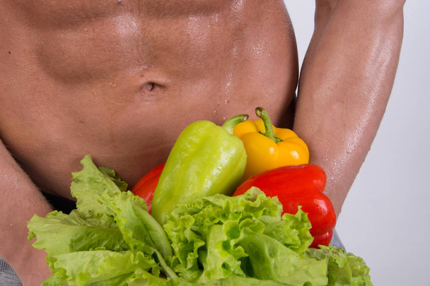 Desporto e dieta. Homem atraente com corpo muscular. Um atlético e legumes. Alimentação saudável
 - Foto, Imagem