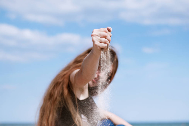joven chica esparciendo arena de su mano
 - Foto, Imagen