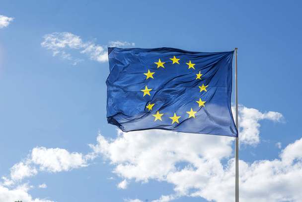 The European Union (EU) Flag waving on a blue sky. - Foto, afbeelding