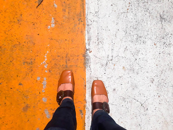Fuß auf dem Fußgängerüberweg, zur Arbeit gehen, Schuhe auf der Straße mit weißem und gelbem Zementhintergrund - Foto, Bild