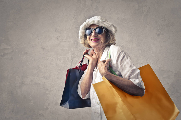Siming elderly lady smiling while holding shopping bag. - Foto, afbeelding