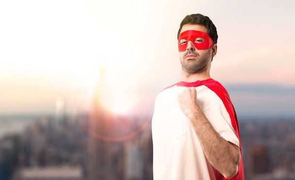 Superheldenmann mit Maske und rotem Umhang stolz und selbstzufrieden in sich selbst verliebt Konzept auf einem Sonnenuntergang Hintergrund - Foto, Bild