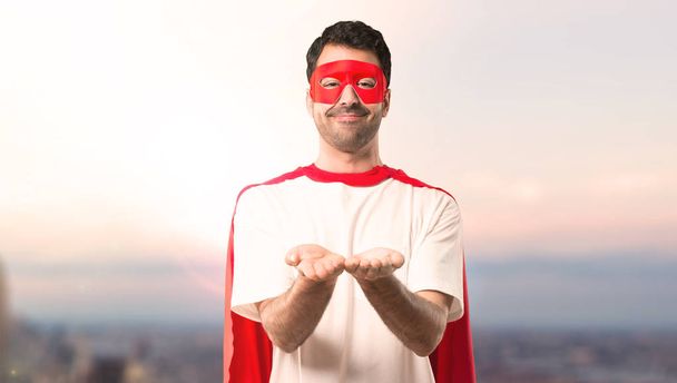 Supersankari mies naamio ja punainen viitta tilalla copyspace kuvitteellinen kämmenellä lisätä mainoksen auringonlaskun taustalla
 - Valokuva, kuva