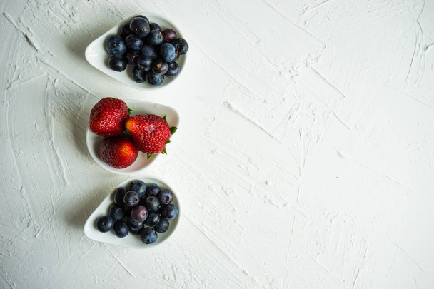 Zomer fruit dessert met bosbessen en aardbeien op witte achtergrond van de concrete - Foto, afbeelding