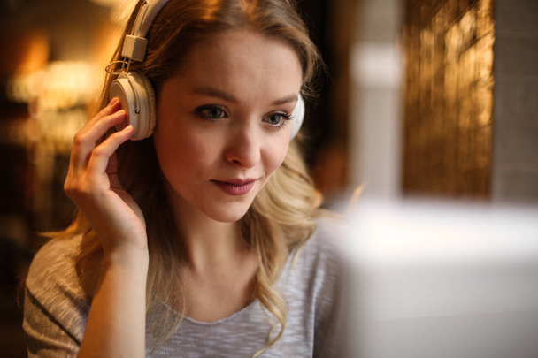 Beautiful woman listening something on her headphones in front of her laptop. - Foto, immagini