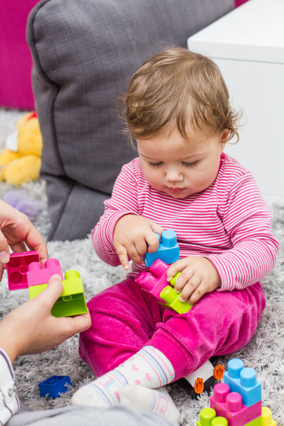 Bambino piccolo che gioca con i giocattoli colorati educativi dei blocchi di plastica a casa
 - Foto, immagini