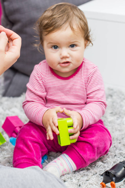 Маленька дитина грає з освітніми барвистими пластиковими блоками іграшки вдома
 - Фото, зображення