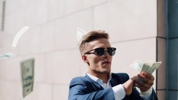 Young happy businessman walking and scatter the dollars on the street near the office center, slow motion. Money rain. Successful business or winning the lottery. Shot on Red Epic - Metraje, vídeo